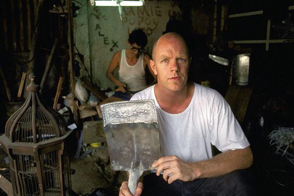 Neil holding shovel with metalwork by Regino Uranquenlo (background) and Romy Iral.